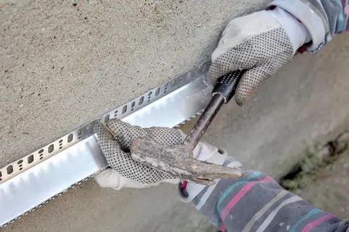Contractor installing metal corner bead for stucco wall repair in Lakeland, FL.